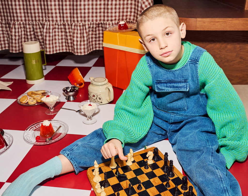 Child wearing turquoise overdyed Kai dungarees showing unique color variations and comfortable fit