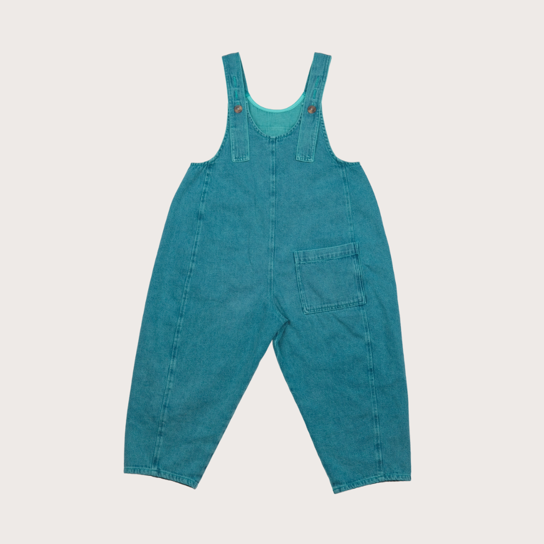 Close-up detail of coral overdyed denim showing artisanal color variation on Kai dungarees